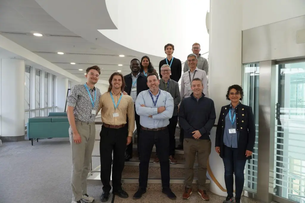 Eleven people standing on stairs smiling at the camera.